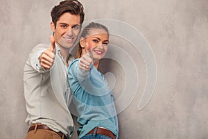 Man with his girlfriend posing in studio showing thumbs up