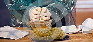 Man with his gloves in a raincoat crushes grapes into a glass plate