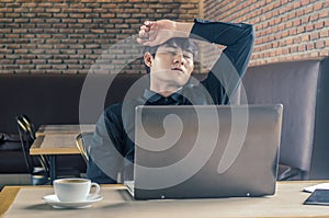 Man with his hand holding his face taking a brake from working