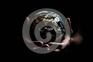 A man in his hands holds a mockup of the planet earth on a black background, the concept of saving ecology on the planet