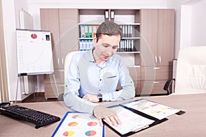 Man in his offce with charts folders on table