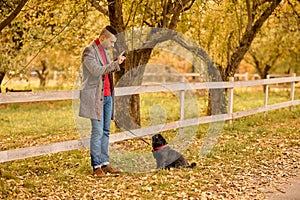 A man and his pet on the background of yellow leaves