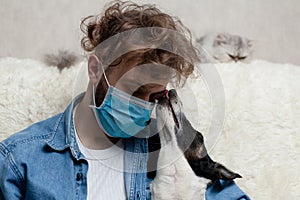 A man with his pet is sitting on a sofa at home. Quarantine coronavirus
