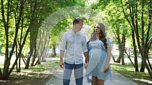 Man and his Pregnant Wife Walking in Summer Park