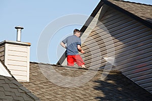 Man on his roof power washing the vinyl siding