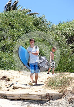 Man and his son arriving at the beach to surf