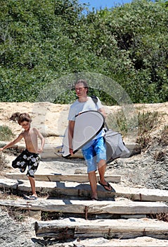 Man and his son arriving at the beach to surf