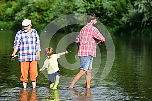 Man with his son and father on river fishing with fishing rods. Happy grandfather, father and grandson with fishing rods