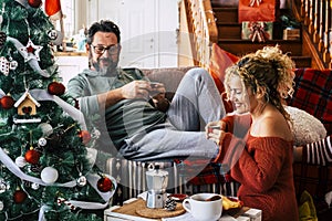 Man with his wife drinking coffee and talking during Christmas celebration at home. Caucasian couple having breakfast on the eve