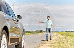 Man hitchhiking and stopping car at countryside