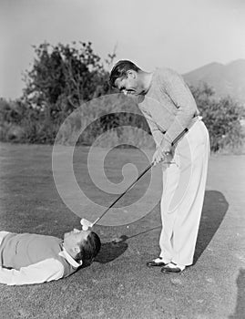 Man hitting golf ball on mans forehead