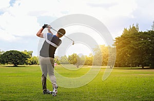 Man hitting golf shot with club on course while summer in the sun.