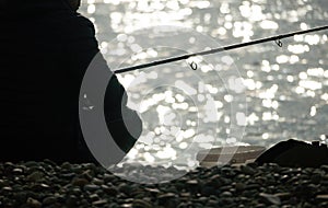 Man hobby fishing on sea tightens a fishing line reel of fish. Calm surface sea. Close-up of a fisherman hands twist