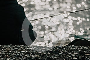 Man hobby fishing on sea tightens a fishing line reel of fish. Calm surface sea. Close-up of a fisherman hands twist