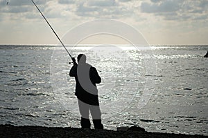 Man hobby fishing on sea tightens a fishing line reel of fish. Calm surface sea. Close-up of a fisherman hands twist