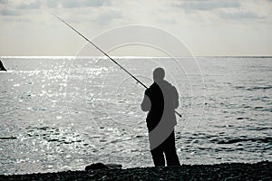 Man hobby fishing on sea tightens a fishing line reel of fish. Calm surface sea. Close-up of a fisherman hands twist