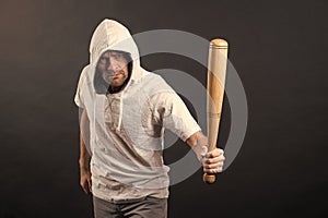 Man hold baseball bat, agression. Hooligan wear hood in hoody, fashion. Gangster guy threaten with bat weapon