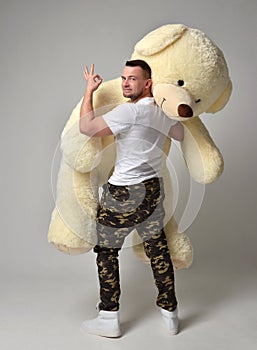 Man hold big teddy bear soft toy as a present to his girlfriend