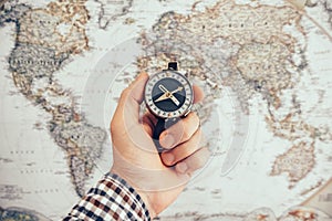 Man hold compass to check the direction with blurred map background. Travel and Business planning concept