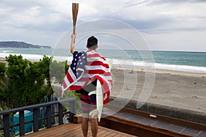 Man hold a flaming torch & American Flag plus Surfboard in Japan . Near surfing competition venue.