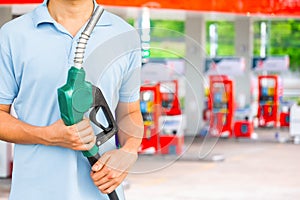 Man hold fuel nozzle to add fuel in car at gas station.