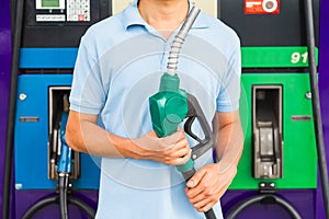 Man hold fuel nozzle to add fuel in car at gas station