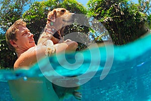 Man hold in hands golden labrador retriever in swimming pool