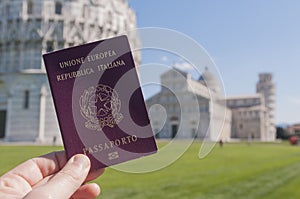 Man hold an italian passport in front of the world famous leaning tower of Pisa