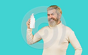 Man hold in liquid soap bottle. Selfcare and beauty products concept. Smiling beautiful male beard with holding shampoo