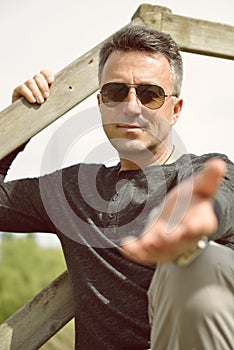 Man hold out one`s hand. Handsome man offers one`s hand. Outdoor male portrait. Single beautiful man posing in spring park