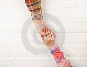 Man hold woman`s hand top view image on wooden background.