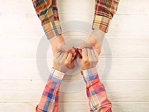 Man hold woman`s hand top view image on wooden background.