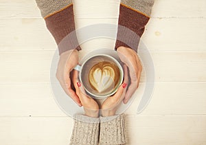 Couple in love holding hands with cup of coffe top view image on white wooden background. Man holds woman`s hand, love cosept. photo