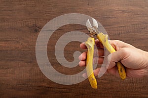 A man hold a yellow cutting plier on wooden background