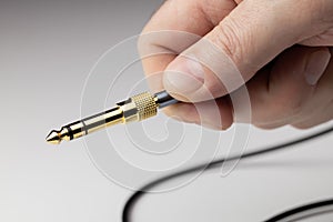 Equipment for connecting devices. The golden plug is held by a man`s fingers.