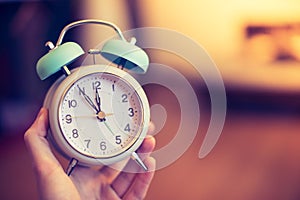 Man is holding an alarm clock in the hand, blurry background