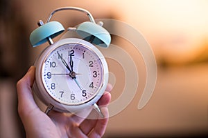 Man is holding an alarm clock in the hand, blurry background