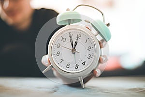 Man is holding an alarm clock in the hand, blurry background