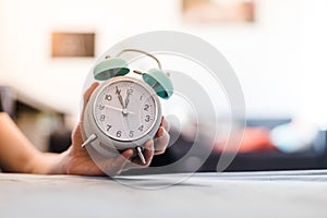 Man is holding an alarm clock in the hand, blurry background