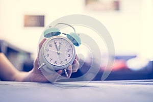 Man is holding an alarm clock in the hand, blurry background