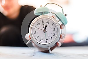 Man is holding an alarm clock in the hand, blurry background