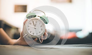 Man is holding an alarm clock in the hand, blurry background