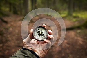 Man holding antique vintage style compass in hand in middle of fir tree forest with nice natural light