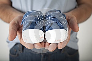 Man holding baby shoes