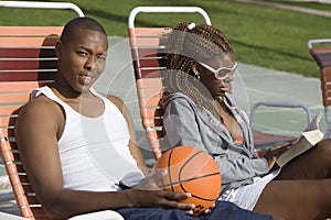 Man Holding Basketball With Friend Reading Book