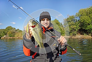 Man holding bass. Fishing scene, catch of fish