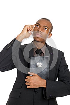 Man holding a bible whilst thinking