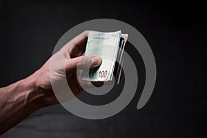 Man holding a bills of money. Euro currency on a black background. HandÂ´s of young man holding a money.