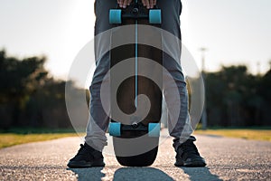 Man holding black longboard skateboard outdoors on sunset