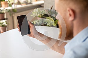 Man holding a black mobile phone with blank screen